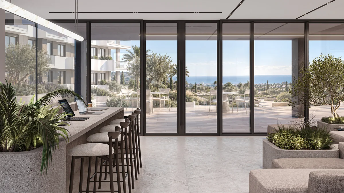 Coworking desks and lounge seating overlooking the landscaped courtyard and sea.